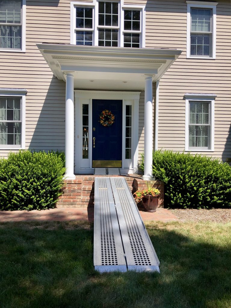 A house with portable ramps leading from the lawn to the front doorway.